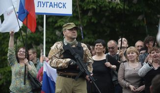 A gunman stands guard as pro-Russian protesters listen to a speaker as they declare independence for the Luhansk region in eastern Ukraine on Monday, May 12, 2014. The words on the nameplate read &quot;Luhansk&quot;. Pro-Russia separatists in eastern Ukraine declared independence Monday for the Donetsk and Luhansk regions following their contentious referendum ballot. (AP Photo/Evgeniy Maloletka)