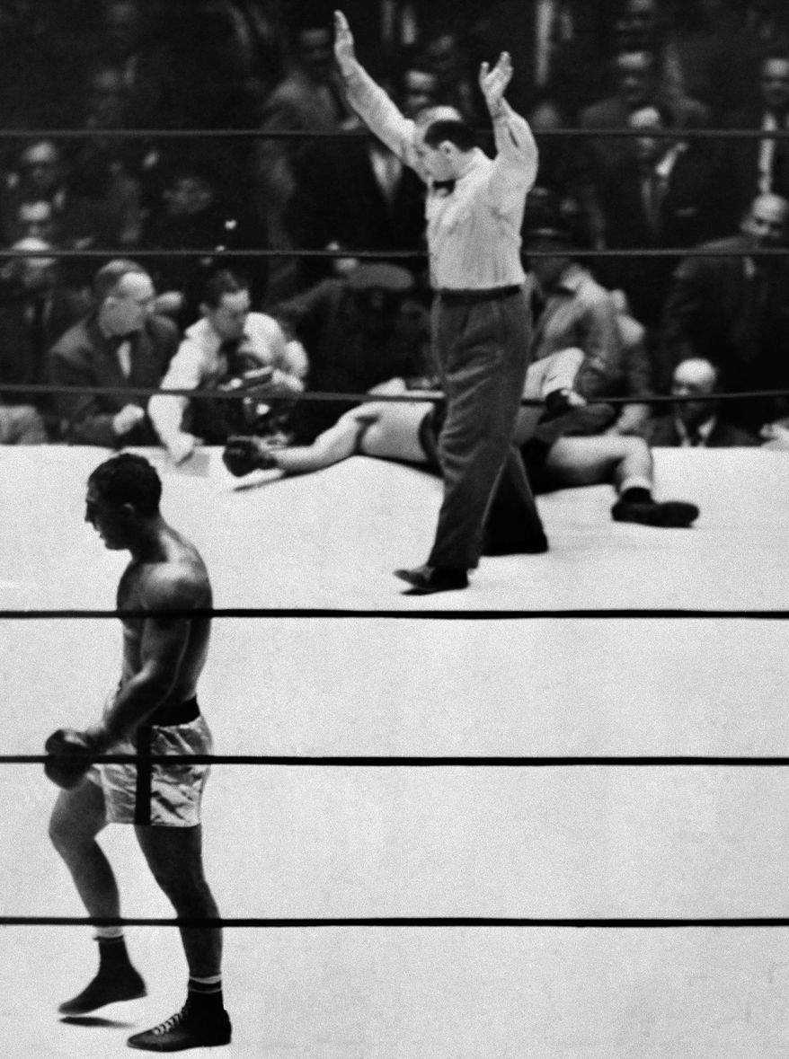 Sprawled outside the ropes with one leg twisted across them, Joe Louis, former heavyweight king, lies on his back in Madison Square Garden Oct. 26, 1951, as his younger, lighter and undefeated opponent, Rocky Marciano, walks to his corner. Referee Ruby Goldstein waves his arms to signal the end of the fight in the eighth round. There was no count and the record books will call it 2:26 of the eighth. Boxing fans will call it the end of a great fighter's career. (AP Photo)