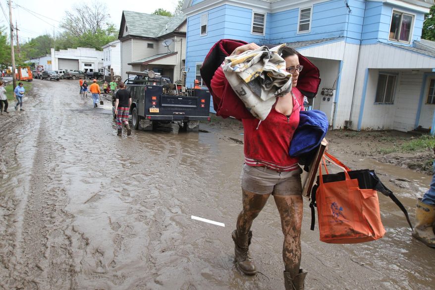 Olivia Rodriguez of Champlin Ave. carries her belongings out of her flooded residence on Champlin Ave., Wednesday, May 14, 2014, in Penn Yan, N.Y. Severe storms that dumped up to five inches of rain have forced evacuations and closed roads in the Finger Lakes region. Authorities tell local media that flash flooding forced some homes to be evacuated early Wednesday morning in the Yates County village of Penn Yan, on the northern end of Keuka Lake 45 miles southeast of Rochester. (AP Photo/Democrat & Chronicle, Tina MacIntyre-Yee) MAGS OUT; NO SALES