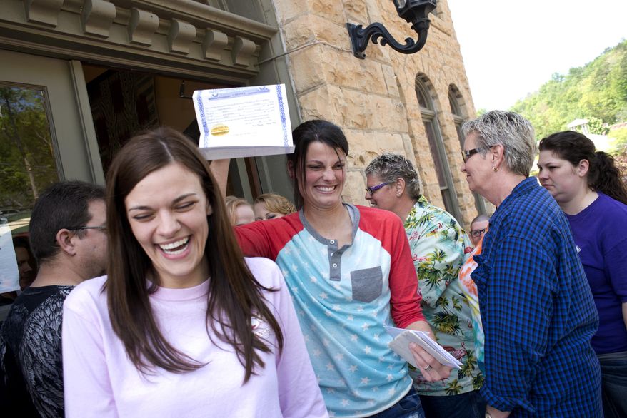 ** FILE ** In this May 10, 2014, file photo, Kristin Seaton, center, of Jacksonville, Ark., holds up her marriage license as she leaves the Carroll County Courthouse in Eureka Springs, Ark., with her partner, Jennifer Rambo, left, of Fort Smith, Ark., in Eureka Springs, Ark. The Arkansas Supreme Court has rejected the state attorney general's request for a stay of a judge's ruling that overturned Arkansas' constitutional ban on gay marriage, Wednesday, May 14, 2014. (AP Photo/Sarah Bentham, file)
