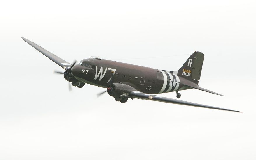 The C-47 'Whiskey 7' makes a pass as it starts the flight for the "Return to Normandy" project being carried out by the Geneseo National Warplane Museum in Geneseo, N.Y., on Thursday May 15 2014.  The Douglas C-47, a World War II transport plane that dropped American paratroopers on Normandy departed from Geneseo, in New York Thursday for a D-Day 70th anniversary commemoration in France. (AP Photo/Democrat & Chronicle, Carlos Ortiz)  MAGS OUT; NO SALES