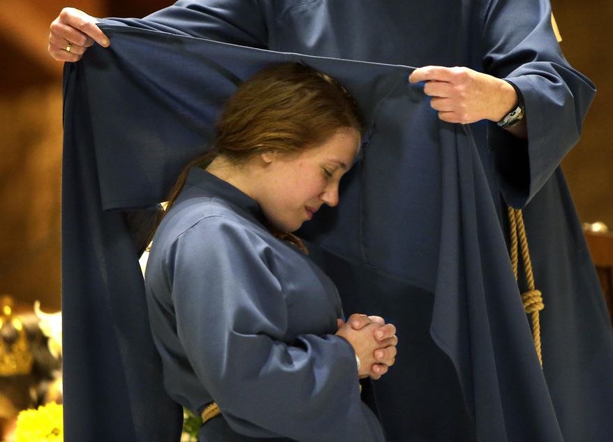 Sister Maria Lucia Stella Maris kneels on the altar at St. Pius X Roman Catholic church as Mother Mary Catherine adds the scapular to her habit May 1, 2014 in Appleton, Wis. The service established the Missionaries of the Word, which is a new religious community of women who will teach young people about Jesus. (AP Photo/The Post-Crescent, Wm. Glasheen)