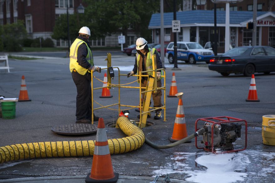 AEP employees work assesing the damage caused by a fire in underground vault near the intersection of Washington and Lafayette Street in South Bend on Friday May 16, 2014. An underground electrical fire left hundreds of homes and businesses in downtown South Bend without power Friday as thousands of people are in town for the University of Notre Dame's weekend commencement ceremonies. (AP Photo/South Bend Tribune, Santiago Flores)