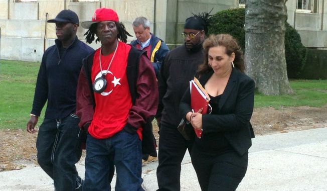 Entertainer Flavor Flav, center, walks out of Nassau County Court in Mineola, N.Y., on Friday, May 16, 2014. His attorney, Indji Bessim, right, said she is still trying to work with prosecutors to settle speeding and unlicensed driving charges against Flav, whose real name is William Drayton.  He was arrested on Long Island in January on his way to his mother&#x27;s funeral. (AP Photo/Frank Eltman)