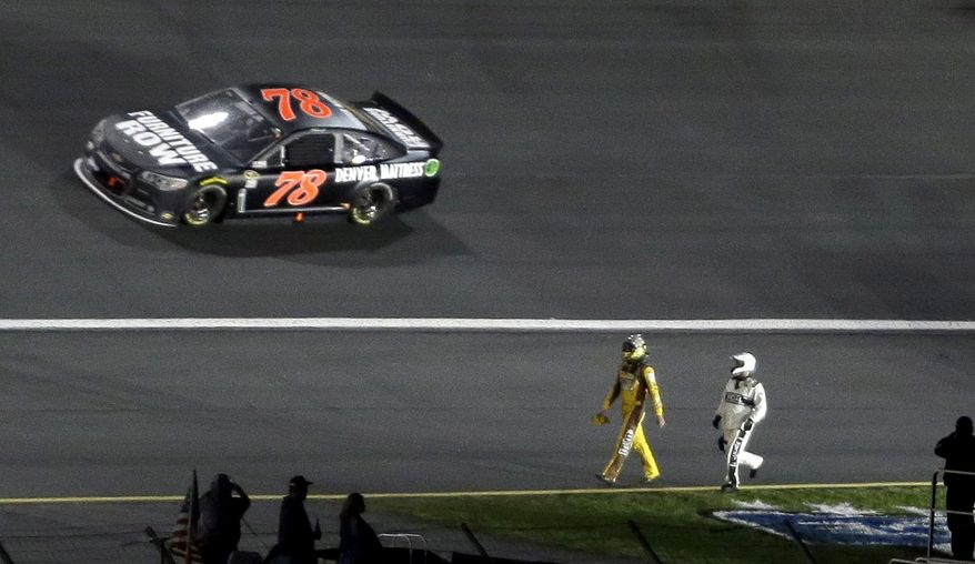 A safety crew worker chases Kyle Busch along the speedway apron after Busch crashed in Turn 3 during the NASCAR Sprint All-Star auto race, as Martin Truex Jr. (78) drives by at Charlotte Motor Speedway in Concord, N.C., Saturday, May 17, 2014. (AP Photo/Gerry Broome)