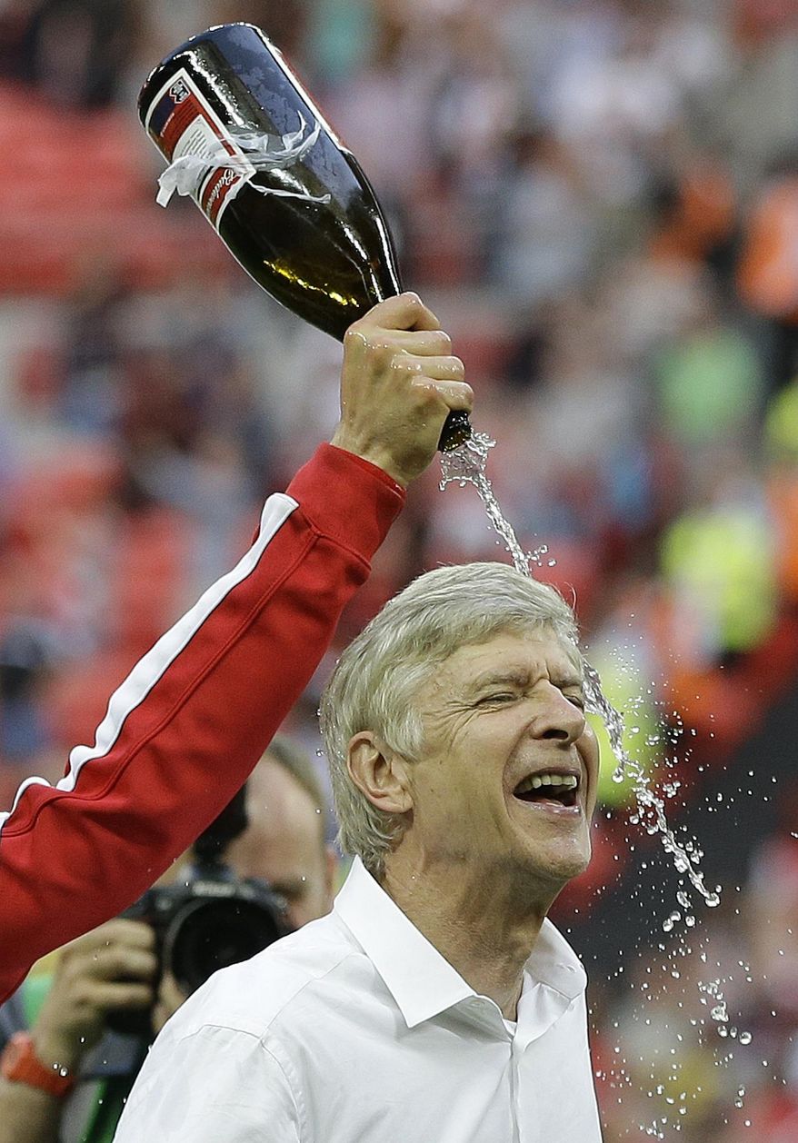 Arsenal's coach Arsene Wenger is doused with champagne by his players as they celebrate after winning the English FA Cup final soccer match between Arsenal and Hull City at Wembley Stadium in London, Saturday, May 17, 2014. Arsenal won 3-2 after extra-time. (AP Photo/Kirsty Wigglesworth)