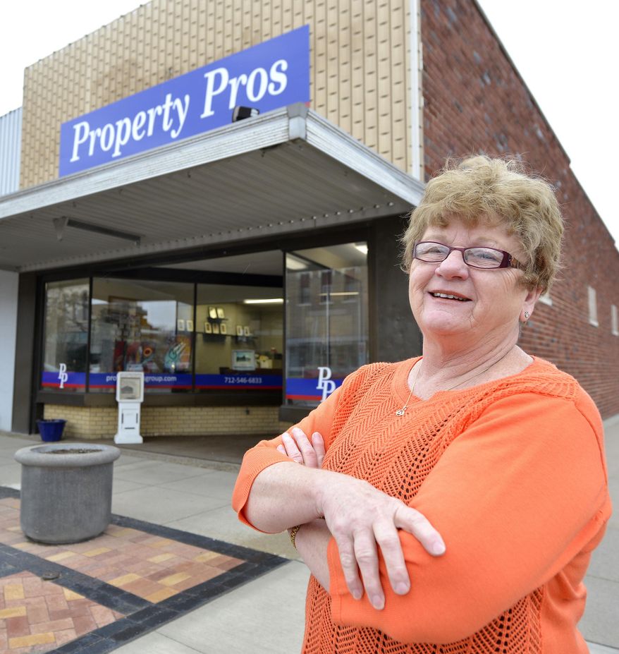 Linda Mayrose, owner of the building housing Property Pros in downtown Le Mars, Iowa, is shown in front of the real estate company Thursday, May 1, 2014. Mayrose is planning to apply for some the $500,000 in community development block grant money the city was awarded for business facade improvements. Mayrose said she plans to remove the tin siding on the upper front of the building.(AP Photo/Sioux City Journal, Tim Hynds)