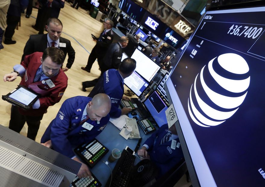 Traders gather at the post that handles AT&T on the floor of the New York Stock Exchange Monday, May 19, 2014. Priming itself for the age of Internet-delivered video, AT&T Inc. said it would buy DirecTV for $48.5 billion in cash and stock, or $95 per share. (AP Photo/Richard Drew)