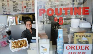 FILE - In this May 26, 2011, file photo, Karen Ramunno of Ramunno&#39;s Pizza and Grill, delivers an order of poutine, a french fry, gravy and cheese dish popular with Canadians, at Old Orchard Beach, Maine. Poutine is one of the 150 new words appearing in Merriam-Webster&#39;s Collegiate Dictionary and the company&#39;s free online database. (AP Photo/Robert F. Bukaty, File)