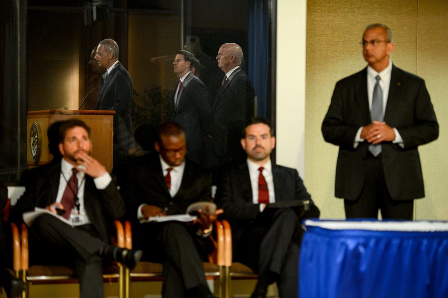 Attourney General Eric Holder, left, announces a criminal indictment against five Chinese military hackers for cyber espionage at a press conference at the Department of Justice, Washington, D.C., Monday, May 19, 2014. The five hackers are identified as Wen Xinyu, Wang Dong, Sun Kailiang, Huang Zhenyu, and Gu Chunhui and are charged with targeting U.S. corporations and labor organizations for commercial advantage. (Andrew Harnik/The Washington Times)