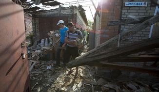 Relatives of Yekaterina Len, 61, try to clean debris in her destroyed house following a shelling in Slovyansk, eastern Ukraine, Tuesday, May 20, 2014. Slovyansk has been the major fighting ground between pro-Russian insurgents and Ukrainian government troops in eastern Ukraine. (AP Photo/Alexander Zemlianichenko)