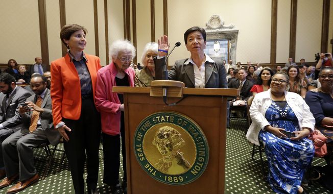 New Washington state Supreme Court Justice Mary Yu recites an oath during her swearing-in to the bench Tuesday, May 20, 2014, in Olympia, Wash. She stands with supporters Anne Levinson, left, Ruth Woo and Phyllis Gutierrez Kenney. Yu, a former King County Superior Court judge, was sworn in as the newest member of the court, marking the first time the high court has had an openly gay justice. Yu, whose mother is from Mexico and father is from China, is also the first Asian American and first female Hispanic member of the court. (AP Photo/Elaine Thompson)