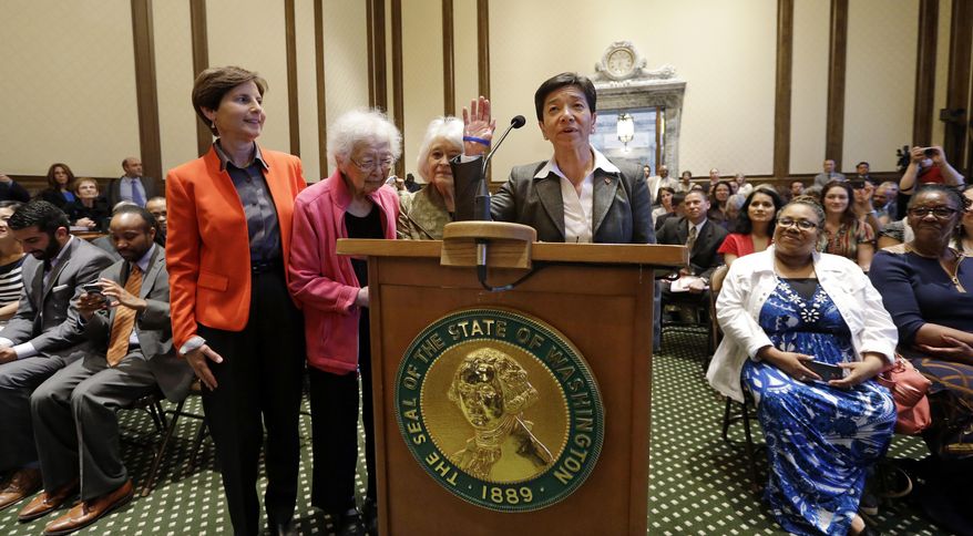 New Washington state Supreme Court Justice Mary Yu recites an oath during her swearing-in to the bench Tuesday, May 20, 2014, in Olympia, Wash. She stands with supporters Anne Levinson, left, Ruth Woo and Phyllis Gutierrez Kenney. Yu, a former King County Superior Court judge, was sworn in as the newest member of the court, marking the first time the high court has had an openly gay justice. Yu, whose mother is from Mexico and father is from China, is also the first Asian American and first female Hispanic member of the court. (AP Photo/Elaine Thompson)