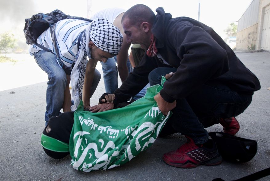 REMOVES REFERENCE TO HOW THE TEEN WAS KILLED, PENDING AN OFFICIAL INVESTIGATION - FILE - In this Thursday, May 15, 2014 file photo, men rush to the aid of Palestinian Mohammad Abu Daher, 17, moments after he is killed in a clash with Israeli troops near the West Bank city of Ramallah. An investigation of the clash between the forces and Palestinian stone-throwers indicates that troops used live fire without justification and in violation of the army’s rules of engagement, an Israeli human rights group said Tuesday, May 20, 2014. The rights group B’Tselem, which said the victim’s actual last name was Salameh, said its findings are based on witness accounts and medical records. Spokeswoman Sarit Michaeli said security camera footage of the incident that surfaced late Monday supports the group’s findings. (AP Photo/Majdi Mohammed, File)