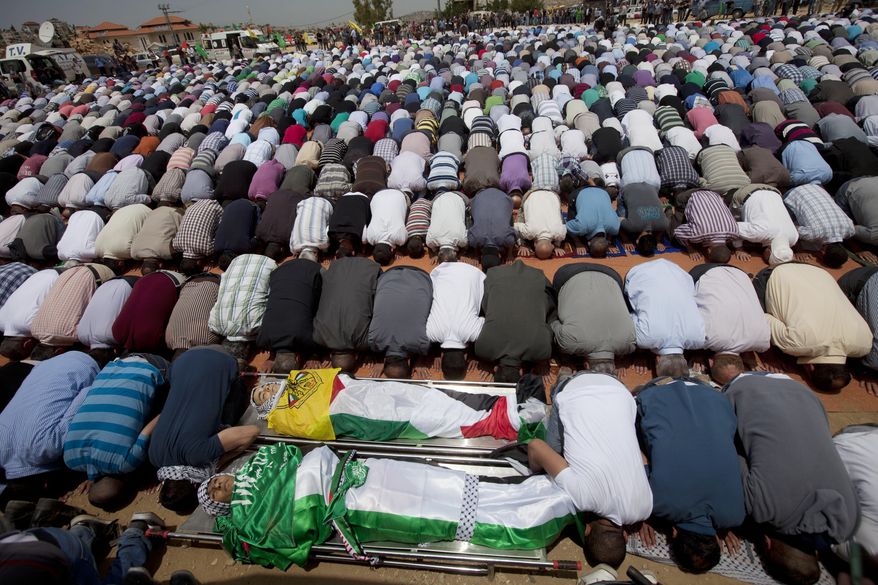 FILE - In this Friday, May 16, 2014, file photo, mourners pray for the bodies of Palestinian teens Mohammad Abu Daher, front, and Nadim Nuwara, behind, the day after they were killed in a clash with Israeli troops, during their funeral in the West Bank city of Ramallah. An investigation of the clash between the forces and Palestinian stone-throwers indicates that troops used live fire without justification and in violation of the army’s rules of engagement, an Israeli human rights group said Tuesday, May 20, 2014. The rights group B’Tselem, which said Mohammad Abu Daher's actual last name was Salameh, said its findings are based on witness accounts and medical records. Spokeswoman Sarit Michaeli said security camera footage of the incident that surfaced late Monday supports the group’s findings. (AP Photo/Majdi Mohammed, File)