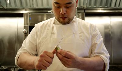 FILE - This April 9, 2008 file photo shows chef David Chang preparing vegetables for dinner at Momofuku Ko in New York. Momofuko Ko is Chang's third restaurant and the hardest to get into, thanks to a new online reservation system that doesn't play favorites and the fact that the restaurant only has 12 seats. (AP Photo/Seth Wenig, File)