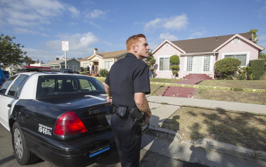 A police officer stands guard in front of the home of actor Michael Jace on Tuesday, May 20, 2014, in Los Angeles. Jace, who played a police officer on the hit TV show "The Shield," was arrested on suspicion of homicide after his wife was found shot to death in their Los Angeles home, authorities said. Police arrived at the couple's home around 8:30 p.m. Monday after a report of shots fired, Officer Chris No said. April Jace, 40, was found dead inside, officials said. Jace was taken into custody and booked early Tuesday on suspicion of homicide, No said. He was being held in a Los Angeles jail in lieu of $1 million bail. (AP Photo/Ringo H.W. Chiu)