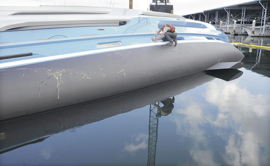 A salvage worker seals window openings on an overturned yacht Monday, May 19, 2014, near Anacortes, Wash. (AP Photo/The Skagit Valley Herald, Scott Terrell)