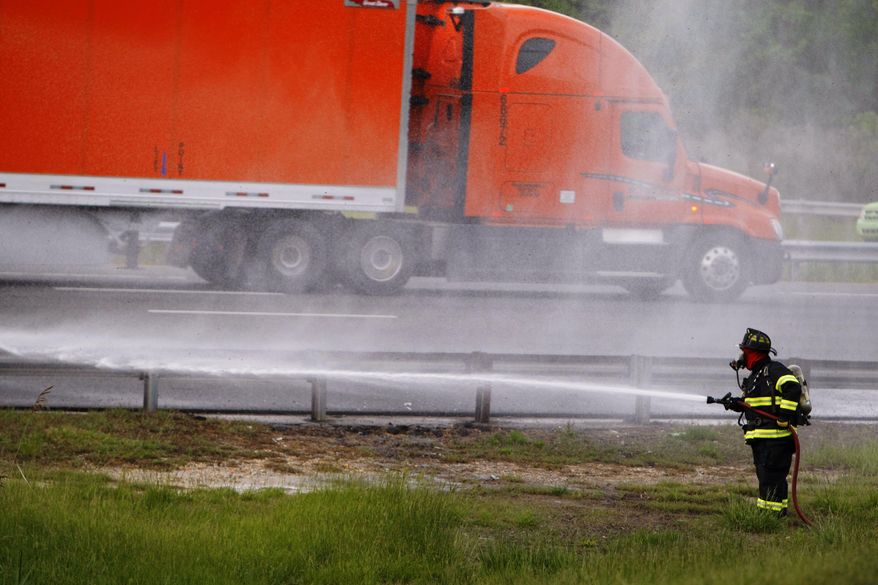 CORRECTS STATE TO DELAWARE INSTEAD OF NEW JERSEY - A firefighter sprays water after a tractor-trailer hauling honeybees overturned on the ramp from Route 896 to Interstate 95 near Newark, Del., releasing as many as 20 million swarming bees, Tuesday, May 20, 2014. Sgt. Paul Shavack said the driver and a passenger were taken to Christiana Hospital with minor injuries. (AP Photo/The Wilmington News-Journal, Suchat Pederson)