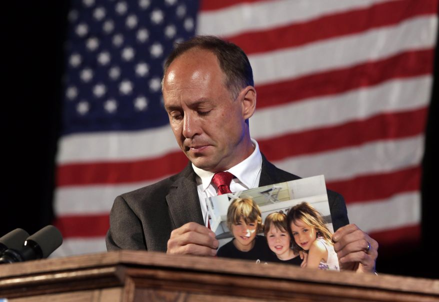 Mark Barden, father of a 7-year-old boy killed at the elementary school shooting in Newtown, Connecticut, holds a photo of his three children during his speech to the opening session of the state's Democratic Convention, in Melville, N.Y., Wednesday, May 21, 2014. The children in the photo are, from left, James Barden, Daniel Barden, who was killed, and Natalie Barden. He told Democrats Wednesday that gun control is a matter of public safety and shouldn't be caught up in politics. (AP Photo/Richard Drew)