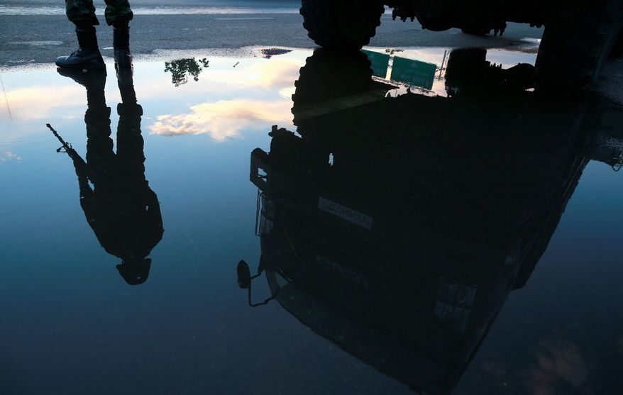 An armed Thai soldier is reflected in a puddle as he guards a road near a pro-government demonstration site on the outskirts of Bangkok. Thailand's army chief Gen. Prayuth Chan-Ocha assumed the role of mediator Wednesday by summoning the country's key political rivals for face-to-face talks one day after imposing martial law. (Associated Press photographs)