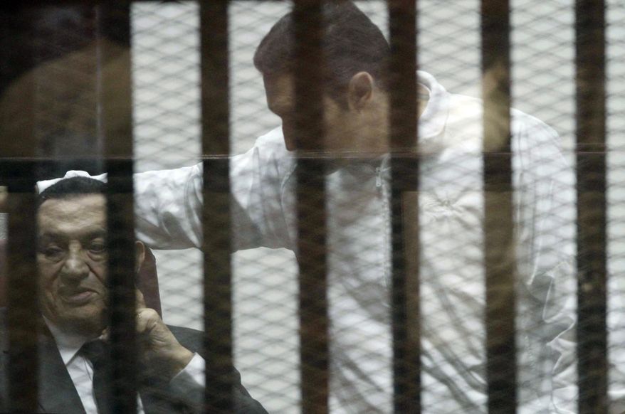 Ousted Egyptian President Hosni Mubarak, sits in a defendants cage, with his son Alaa, right, during a court hearing in Cairo, Egypt, Wednesday, May 21, 2014. An Egyptian court has convicted Mubarak of embezzlement and sentenced him to three years in prison. Mubarak's two sons, one-time heir apparent Gamal and wealthy businessman Alaa, were also convicted Wednesday of graft and sentenced to four years in prison each in the same case. (AP Photo/ Hassan Mohammed)
