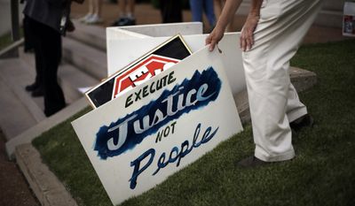 A death penalty opponent picks up a sign at the start of a vigil outside St. Francis Xavier College Church hours before the scheduled execution of Missouri death row inmate Russell Bucklew on Tuesday, May 20, 2014, in St. Louis. A federal appeals court panel granted a temporary halt to the execution of Bucklew on Tuesday evening citing concerns that he could suffer during lethal injection due to a rare medical condition. The panel&#39;s ruling could be overturned by the full appeals court, or by the U.S. Supreme Court. (AP Photo/Jeff Roberson)