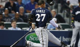 Milwaukee Brewers center fielder Carlos Gomez (27) loses his helmet as he swings and misses in the seventh inning of a baseball game against Atlanta Braves Monday, May 19, 2014 in Atlanta. (AP Photo/John Bazemore)