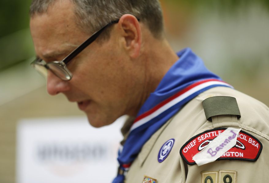 Geoffrey McGrath, a gay Boy Scout troop leader and Eagle Scout from Seattle, who had his membership in the Scouts revoked by the organization earlier this year, wears a piece of tape with the word "banned" written on it on his scout council shoulder patch as he speaks in front of a group of Boy Scouts and scout leaders, Wednesday, May 21, 2014, outside the headquarters of Amazon.com in Seattle. The group delivered a petition bearing more than 125,000 signatures, urging Amazon to stop donating money to the Boy Scouts due to the organization's policy of excluding openly gay adults from leadership positions, despite recently accepting gay youth as scouts. (AP Photo/Ted S. Warren)