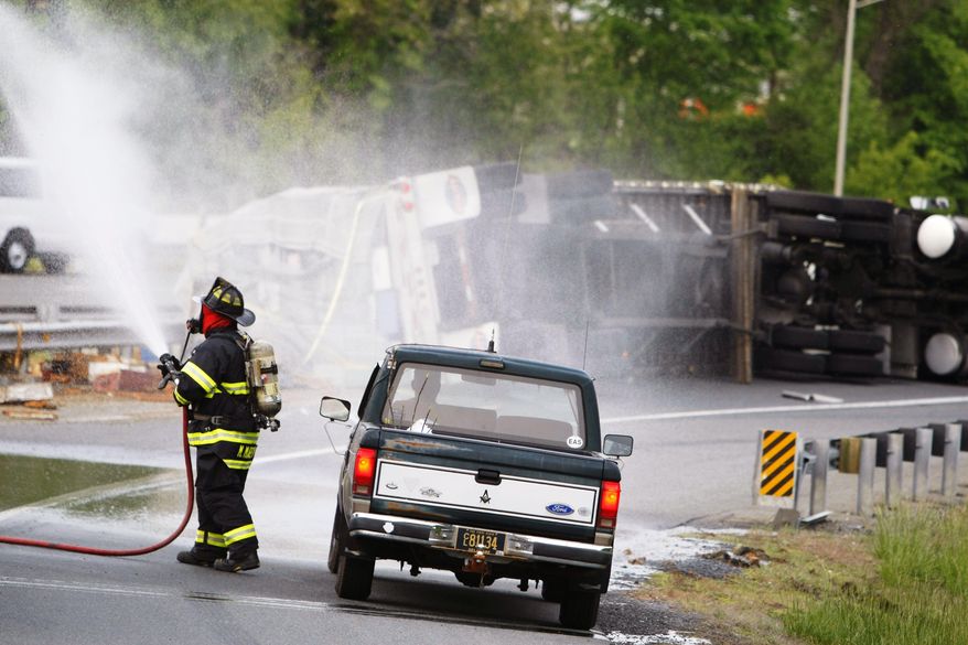 CORRECTS STATE TO DELAWARE INSTEAD OF NEW JERSEY - A firefighter sprays water after a tractor-trailer hauling honeybees overturned on the ramp from Route 896 to Interstate 95 near Newark, Del., releasing as many as 20 million swarming bees, Tuesday, May 20, 2014. Sgt. Paul Shavack said the driver and a passenger were taken to Christiana Hospital with minor injuries. (AP Photo/The Wilmington News-Journal, Suchat Pederson)