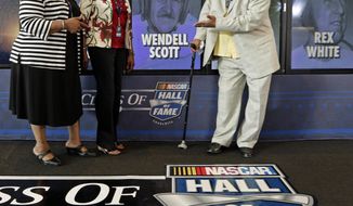 Wendell Scott Jr, right, Mable Scott, left, and Deborah Davis, center, pose for photos after Wendell Scott was named as one of five inductees into the NASCAR Hall of Fame class of 2015 during an announcement in Charlotte, N.C., Wednesday, May 21, 2014. (AP Photo/Chuck Burton)