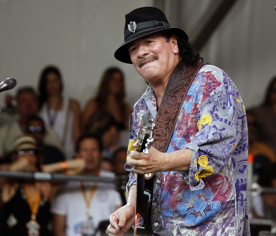 FILE - This April 25, 2014 file photo shows Carlos Santana performing during the New Orleans Jazz and Heritage Festival in New Orleans. Santana’s latest album, “Corazon,” debuted at No. 9 on the Billboard 200 albums chart last week. It features Juanes, Gloria Estefan and Miguel, and Santana said it wasn’t hard finding “Cinderella or Cinderfella” to guest on the songs, which he calls “glass slippers.” (AP Photo/Doug Parker, File)