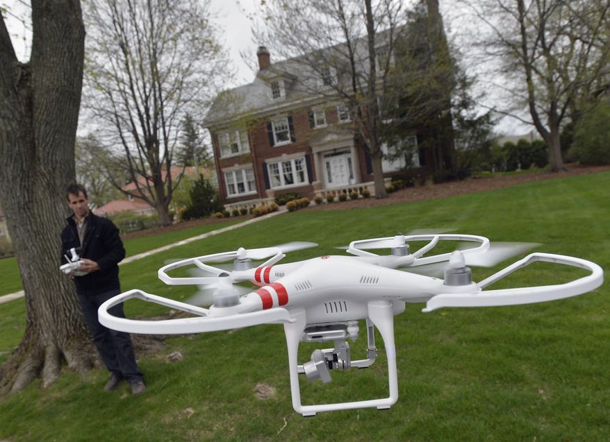 ** FILE ** A man demonstrates the use of a drone in Peoria, Ill., April 29, 2014. (Associated Press)
