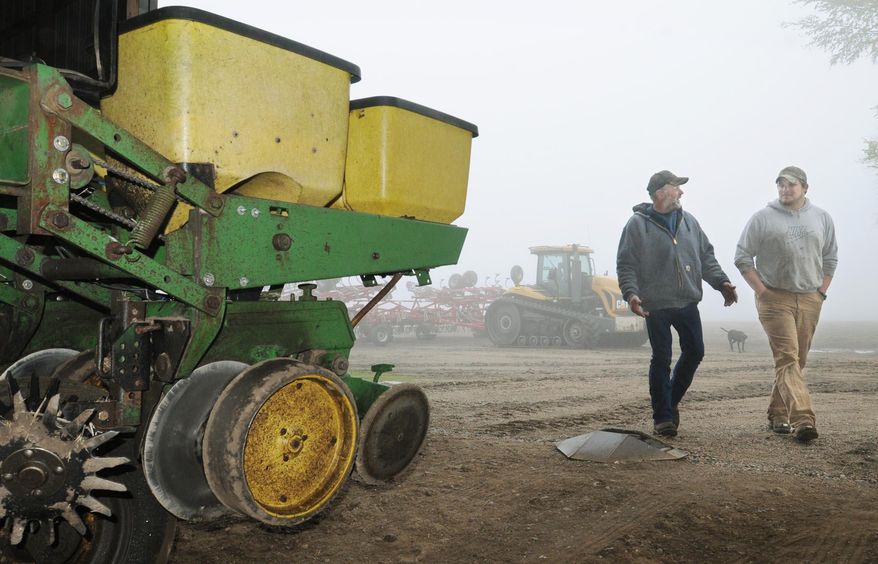 Le Sueur County, Minn. farmer Bob Braun, left, and farming partner Ryan Thelemann walk past a planter idled by wet weather in Le Sueur, Minn., on Tuesday, May 20, 2014. Wet weather has delayed spring planting for many farmers in Minnesota, threatening yields andcrop insurance benefits. (AP Photo/The Mankato Free Press, John Cross)
