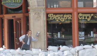 FILE - In this May 31, 2013, file photo, sandbags are piled around the Parlor City Pub and Eatery in Cedar Rapids, Iowa, where workers placed a cardboard cutout of a man drinking beer. Congress sent the White House a $12.3 billion water projects bill half the size of its last one seven years ago — before the economy sank into a deep recession that helped swell the government&#39;s debt and before lawmakers swore off cherry-picking pet projects for folks back home.  (AP Photo/Ryan J. Foley, File)