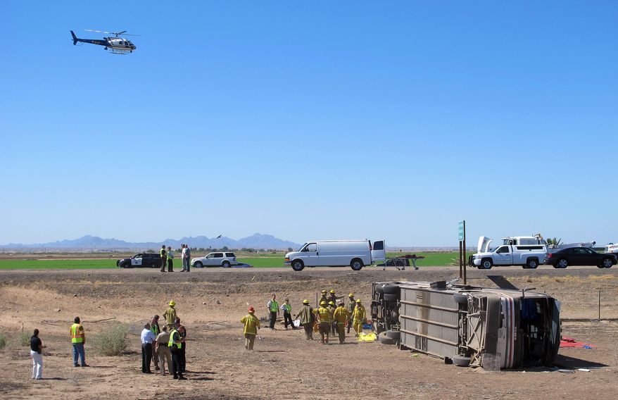 Emergency personnel respond to the scene of a fatal accident in Blythe, Calif. on Wednesday, May 21, 2014. A tractor-trailer spilled a load of steel pipes onto a highway, triggering a bus crash Wednesday that killed four people and seriously injured several others on the main road linking Southern California and Arizona, authorities said. (AP Photo/Brian Skoloff)