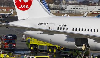 In this Jan. 7, 2013, file photo, a Japan Airlines Boeing 787 jet aircraft is surrounded by emergency vehicles while parked at a Terminal E gate at Logan International Airport in Boston as a fire chief looks into the cargo hold. (AP Photo/Stephan Savoia, File)