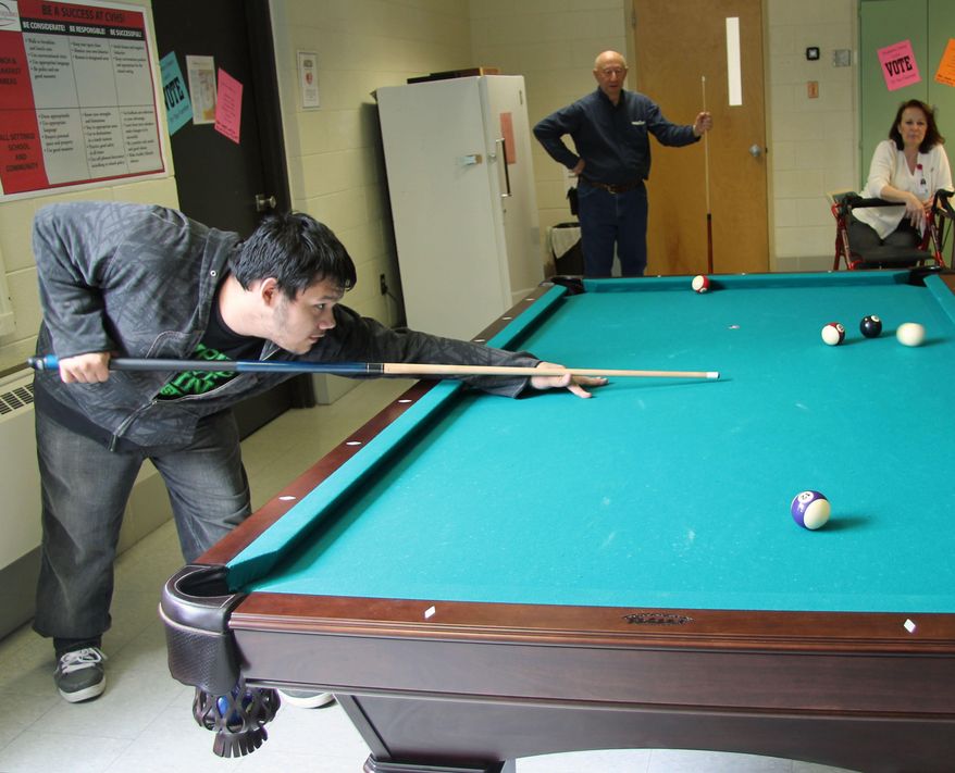 Andrew Martinez takes a shot as his opponents Gunther Peterson and Debra Frederick look on at Chippewa Valley High School in Chippewa Falls, Wis. on May 15, 2014. Martinez drafted a letter to Swimrite in Eau Claire, who responded by providing Chippewa Valley High School with a new pool table. The students were asked to pay it forward, which they did by inviting residents of the Veteran's Home across the street to play games with them. (AP Photo/The Chippewa Herald-Telegram, Elizabeth Dohms)