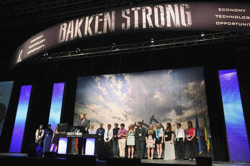 This May 21, 2014 photo provided by the North Dakota Petroleum Council shows a group of eight-graders from West Fargo’s Cheney Middle School standing behind North Dakota Attorney General Wayne Stenehjem as he addresses the Williston Basin Petroleum Conference in Bismarck, N.D. The students were at the conference to present projects addressing problems caused by or related to oil development in the state. (AP Photo/North Dakota Petroleum Council, Renae Mitchell)