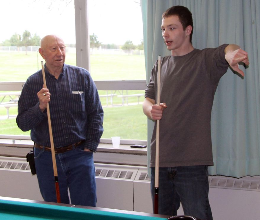 Alexander King, right, a junior at Chippewa Valley High School, talks with Veteran's Home resident Gunther Peterson during a break from their game of pool Thursday, May 15, 2014 at Chippewa Valley High School in Chippewa Falls, Wis. Andrew Martinez drafted a letter to Swimrite in Eau Claire, who responded by providing Chippewa Valley High School with a new pool table. The students were asked to pay it forward, which they did by inviting residents of the Veteran's Home across the street to play games with them. (AP Photo/The Chippewa Herald-Telegram, Elizabeth Dohms)