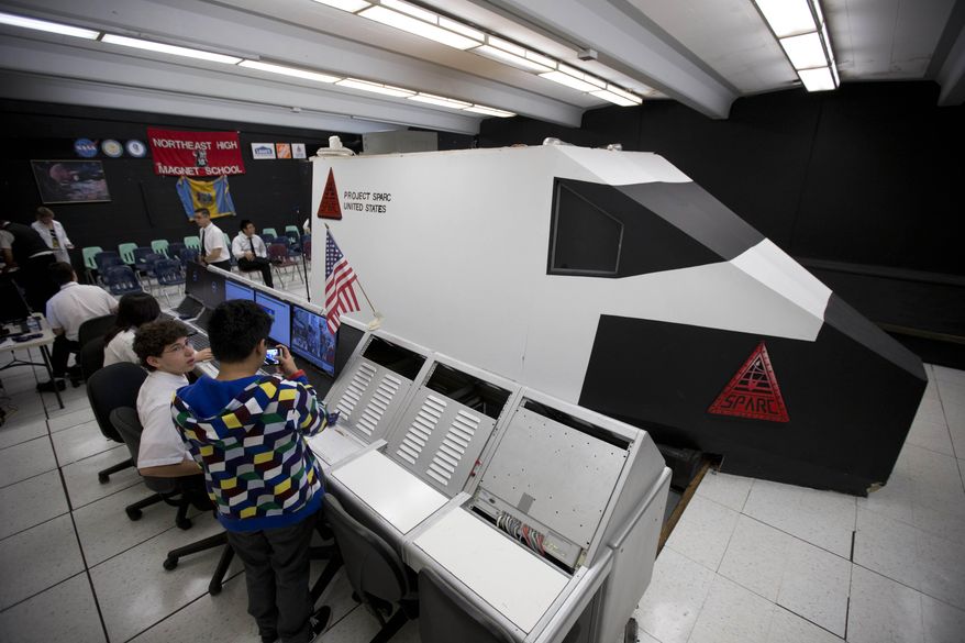 Students at Project SPARC, the nickname, of Northeast High School’s Space Research Center make preparations at mission control, left, next to a 21-foot-long shuttle simulator, for a virtual space mission on a, Thursday, May 22, 2014, in Philadelphia. School officials say SPARC launched about 50 years ago as the first NASA-recognized high school space program. But funding problems threatened to end it this year. Alumni raised money to save SPARC, and students “blasted off” on a two-day mission Thursday. They are expected to stay the night at school to finish the mission Friday. (AP Photo/Matt Rourke)