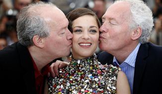 Director Jean-Pierre Dardenne, right, and director Luc Dardenne, left, kiss actress Marion Cotillard as they pose for photographers during a photo call for Two Days, One Night (Deux jours, une nuit) at the 67th international film festival, Cannes, southern France, Tuesday, May 20, 2014. (AP Photo/Alastair Grant)