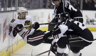 Chicago Blackhawks center Marcus Kruger, left, is checked by Los Angeles Kings defenseman Alec Martinez, and left wing Tanner Pearson, top, during the first period of Game 3 of the Western Conference finals of the NHL hockey Stanley Cup playoffs in Los Angeles, Saturday, May 24, 2014. (AP Photo/Chris Carlson)