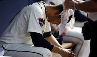 Atlanta Braves&#39; Andrelton Simmons has a wet towel draped over his head by trainer Jim Lovell as he sits in the dugout in the fourth inning of a baseball game against the Colorado Rockies, Saturday, May 24, 2014, in Atlanta. (AP Photo/David Goldman)