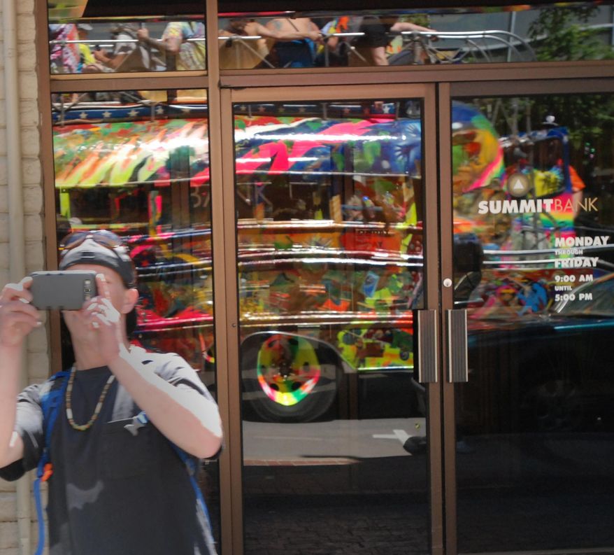 A man snaps a photo of the latest version of late author Ken Kesey's psychedelic bus Further, reflected in a window, as it drives through Eugene, Ore. Zane Kesey, the author's son, is on Kickstarter raising money for a trip across America commemorating the 50th anniversary of his father's 1964 trip, which became an icon of the 1960s. (AP Photo/Jeff Barnard)