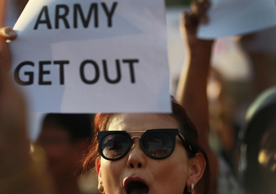 An anti-coup protester holds a banner and shouts during a demonstration at the Victory Monumet in Bangkok, Thailand Saturday, May 24, 2014. Thailand's coup leaders said Saturday that they would keep former Prime Minister Yingluck Shinawatra, Cabinet members and anti-government protest leaders detained for up to a week to give them "time to think" and to keep the country calm. They also summoned outspoken academics to report to the junta. (AP Photo/Wason Wanichakorn)