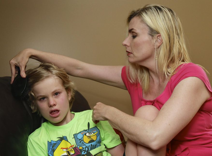 In this May 23, 2014 photo, Colleen Jankovich brushes the hair of her 11-year-old autistic son, Matthew, who is non-verbal and requires 24/7 care, in Omaha, Neb. Jankovich was forced to stop her son’s ABA treatment after just weeks because insurance would not pay for it. (AP Photo/Nati Harnik)
