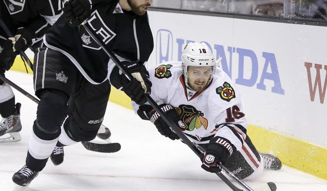 Los Angeles Kings defenseman Willie Mitchell, left, steals the puck from Chicago Blackhawks center Marcus Kruger during the third period of Game 3 of the Western Conference finals of the NHL hockey Stanley Cup playoffs in Los Angeles, Saturday, May 24, 2014. (AP Photo/Chris Carlson)