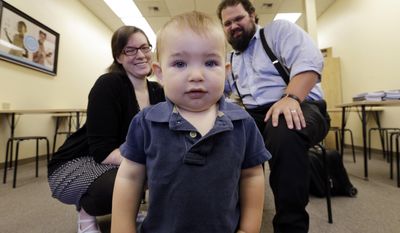 In this May 21, 2014 photo, Amanda Lewis, left, and her husband Ivan look on as their son Fletcher, 1, wanders away from them to get a closer look at the camera while being photographed in Mukilteo, Wash. The family has long used a naturopathic doctor, covered by their private insurance plan, as their primary care provider. But up until this year, Lewis had to pay $95 a visit for her young son because naturopaths in Washington state weren&#39;t authorized to be part of the Medicaid plan that he was covered under. (AP Photo/Elaine Thompson)