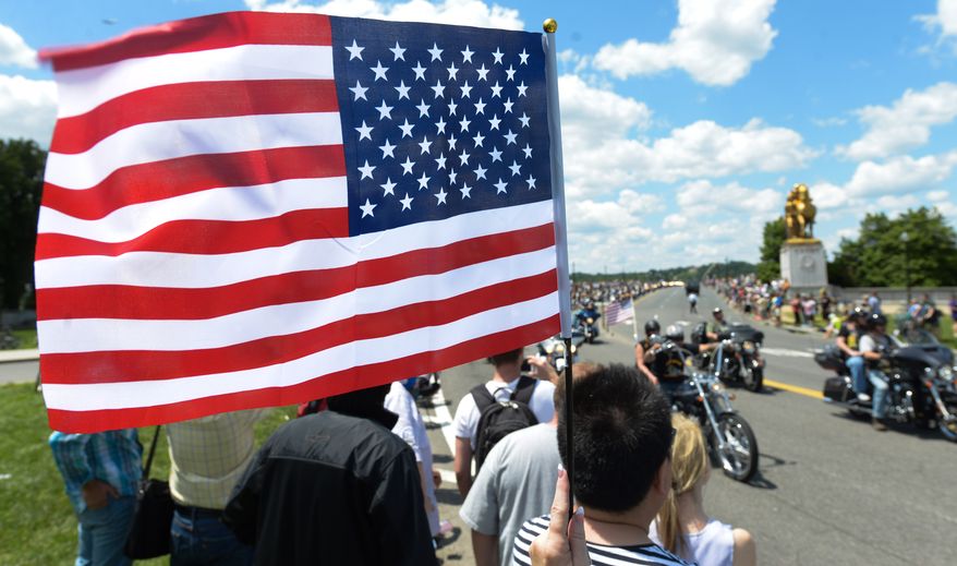 An unidentified person waves the U.S. Flag during the Rolling Thunder in the 25th anniversary of the Rolling Thunder Ride for Freedom at the base of the Memorial Bridge on Sunday, May 25. Khalid Naji-Allah/ Special for the Washington Times
